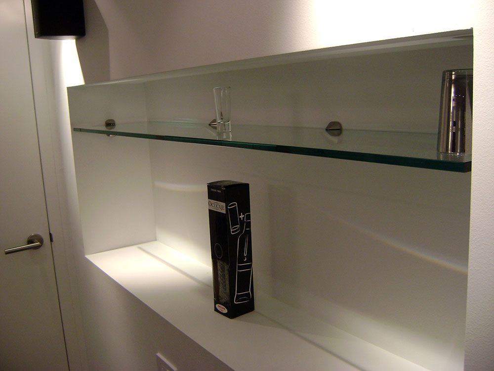 A white shelf with glass shelves and a box on it