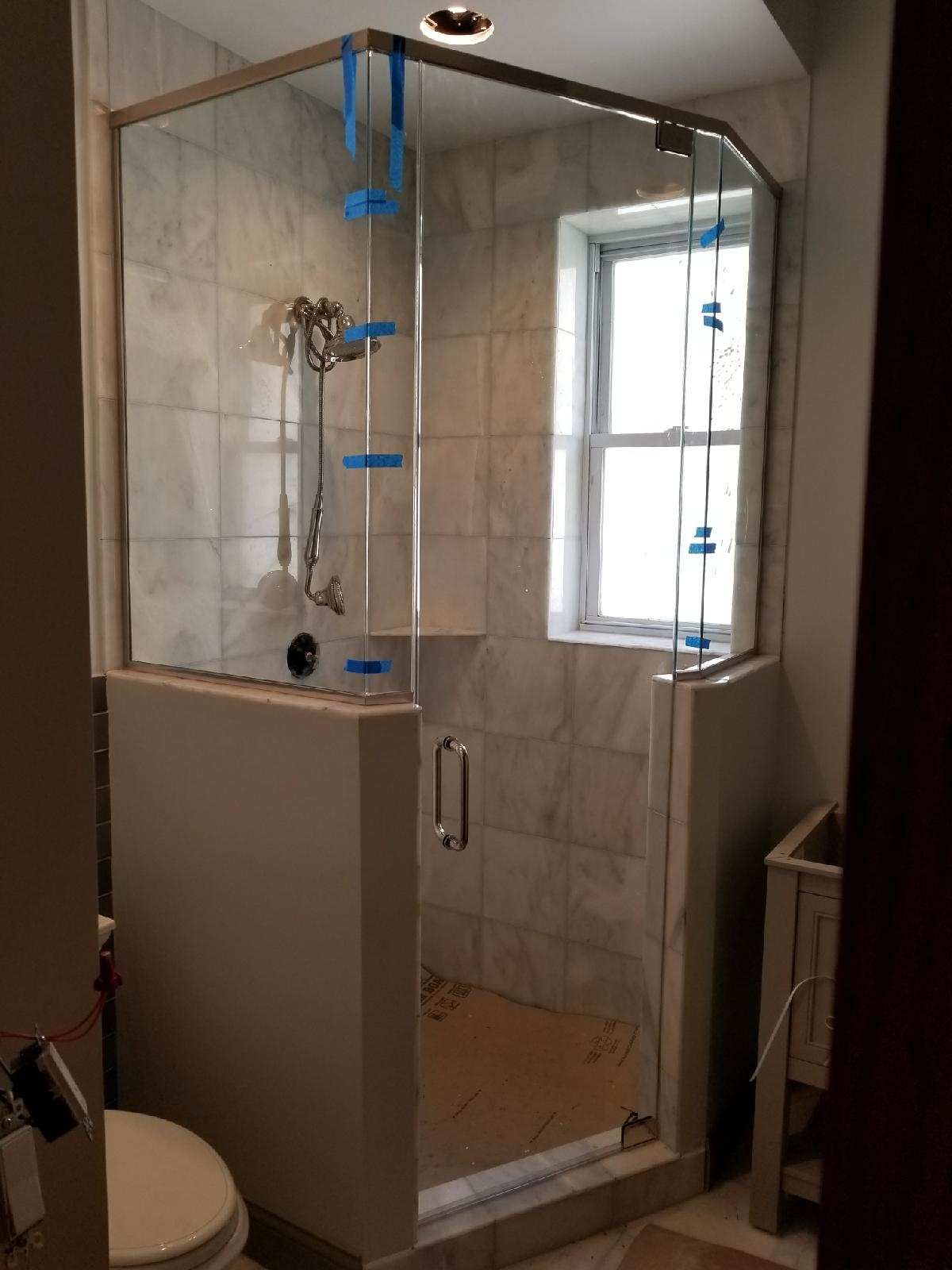 A bathroom with a glass shower door and a toilet.