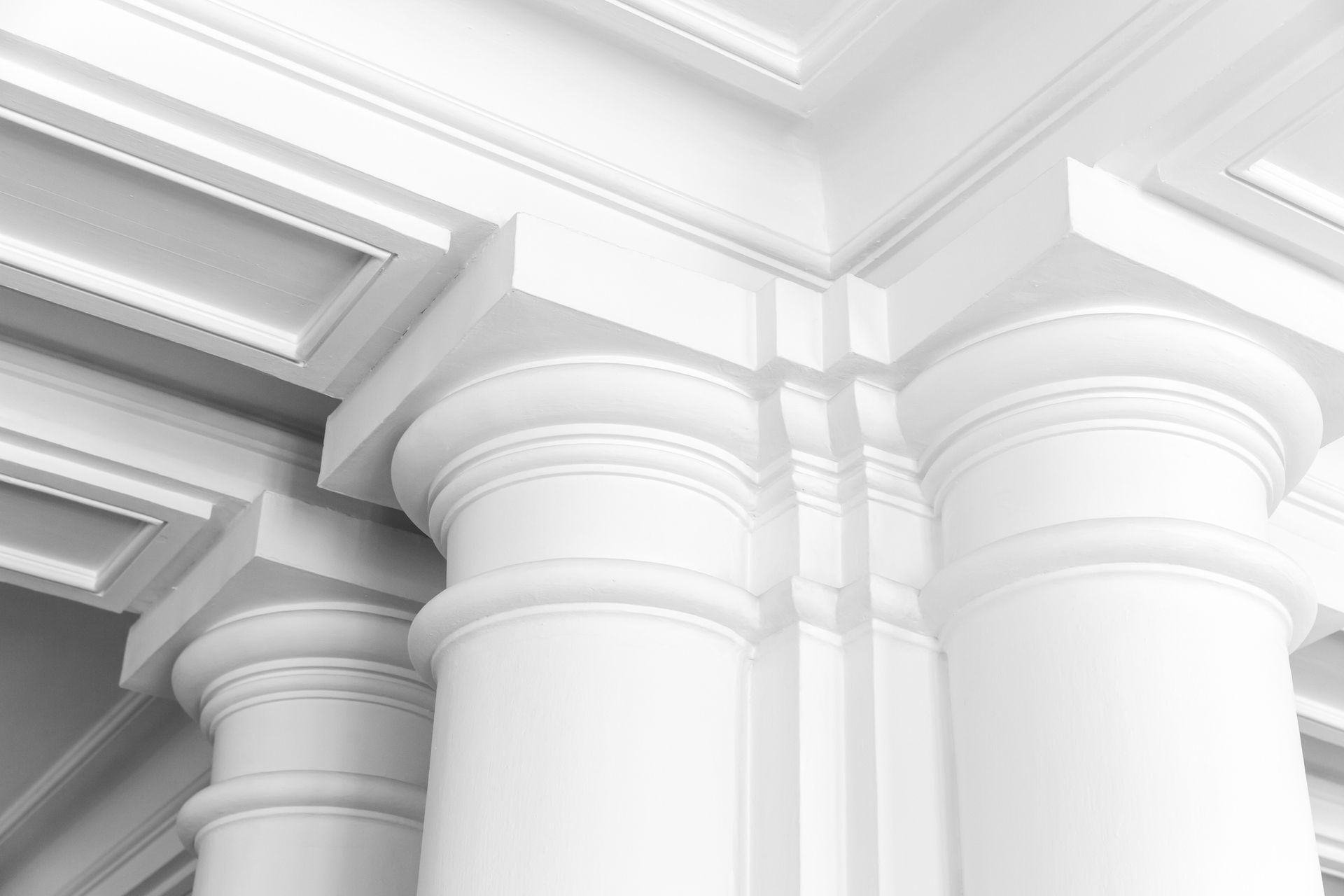 White classical-style columns and ornate ceiling corner, possibly a building exterior or interior.