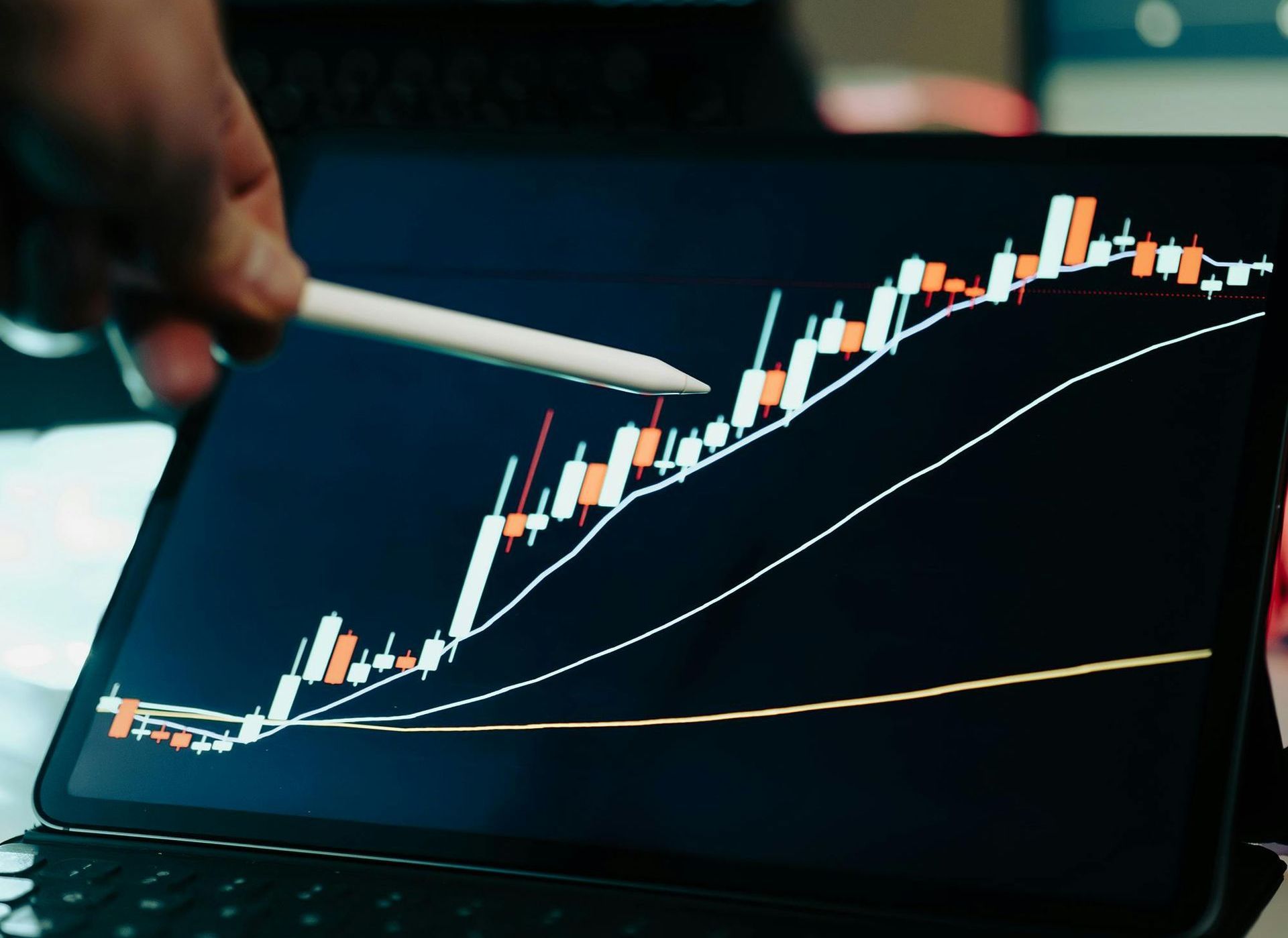 A person is pointing at a graph on a tablet with a pencil.
