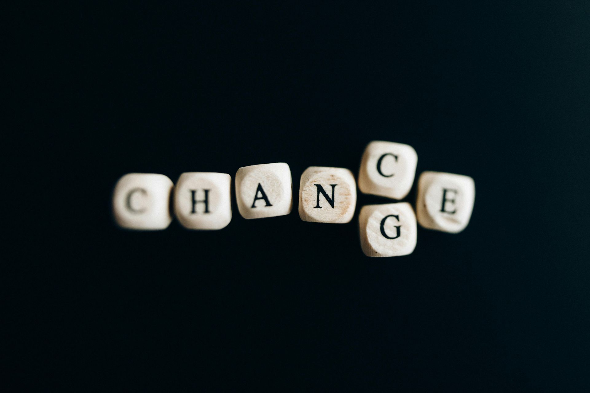 The word change is written on wooden dice on a black background.