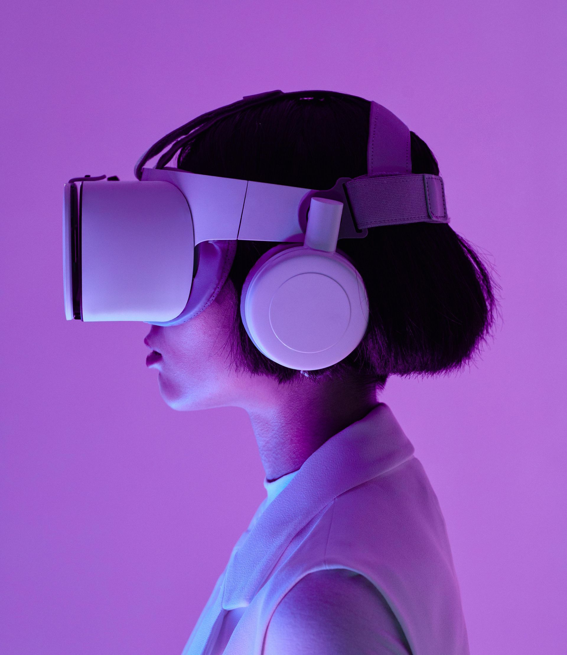 Person wearing a VR headset and headphones in a purple-lit space.