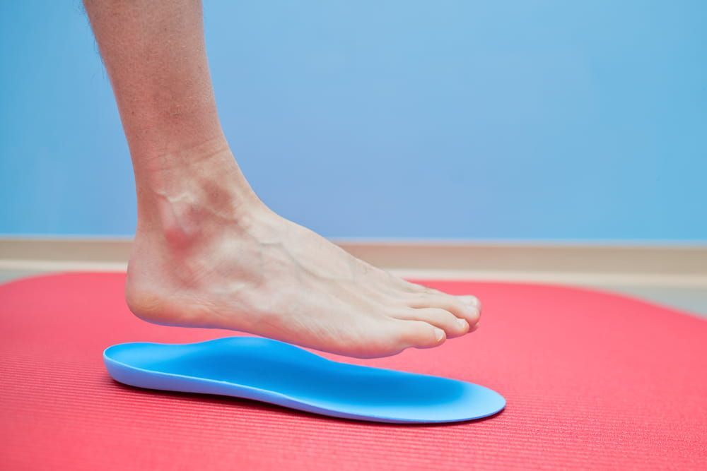 A Person 's Foot is Standing on a Red Mat Next to a Blue Insole — Sugarland Chiropractic Centre in Avoca, QLD