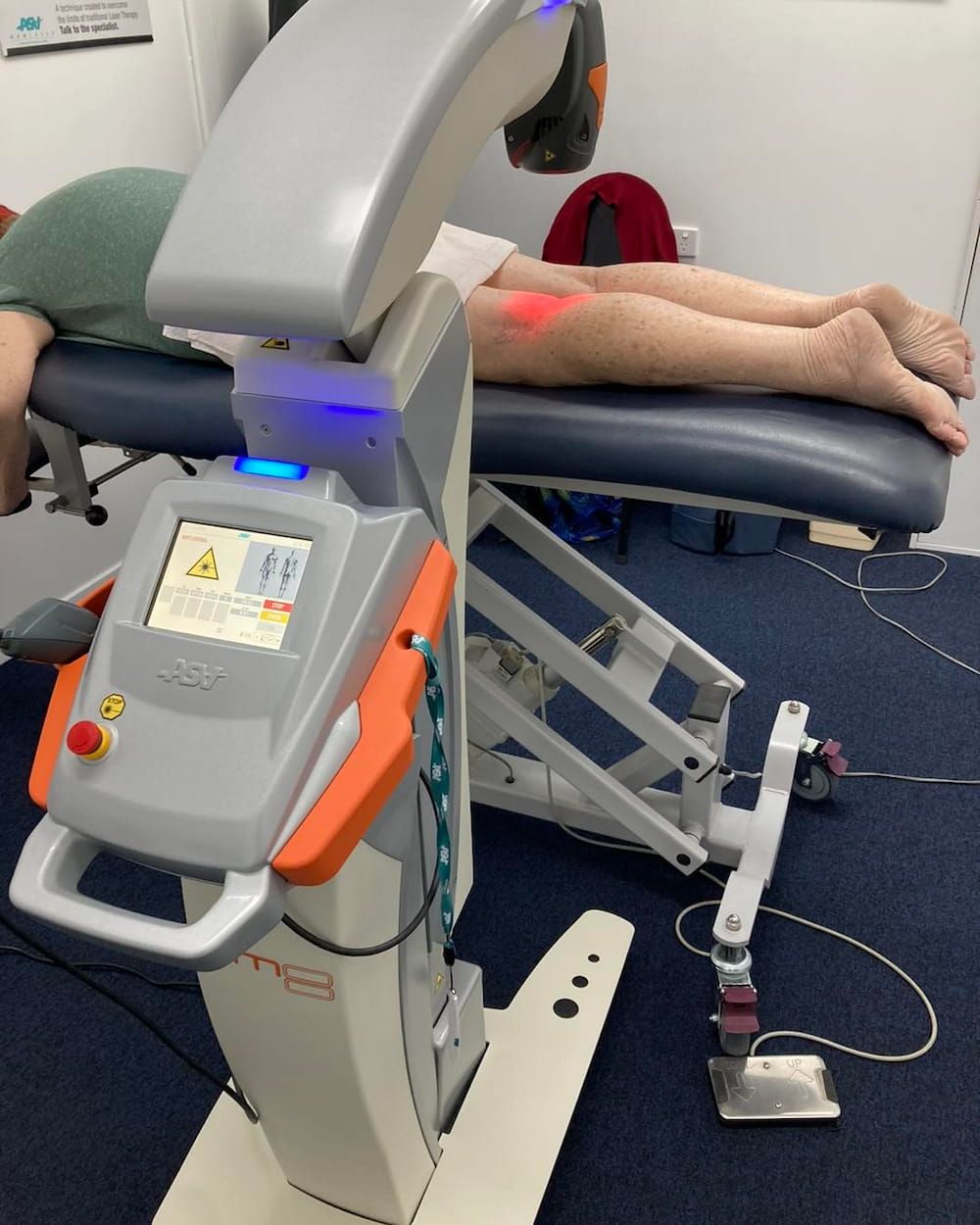 A Person is Laying on a Table With a Machine That Says ' Tcm ' on It — Sugarland Chiropractic Centre in Avoca, QLD