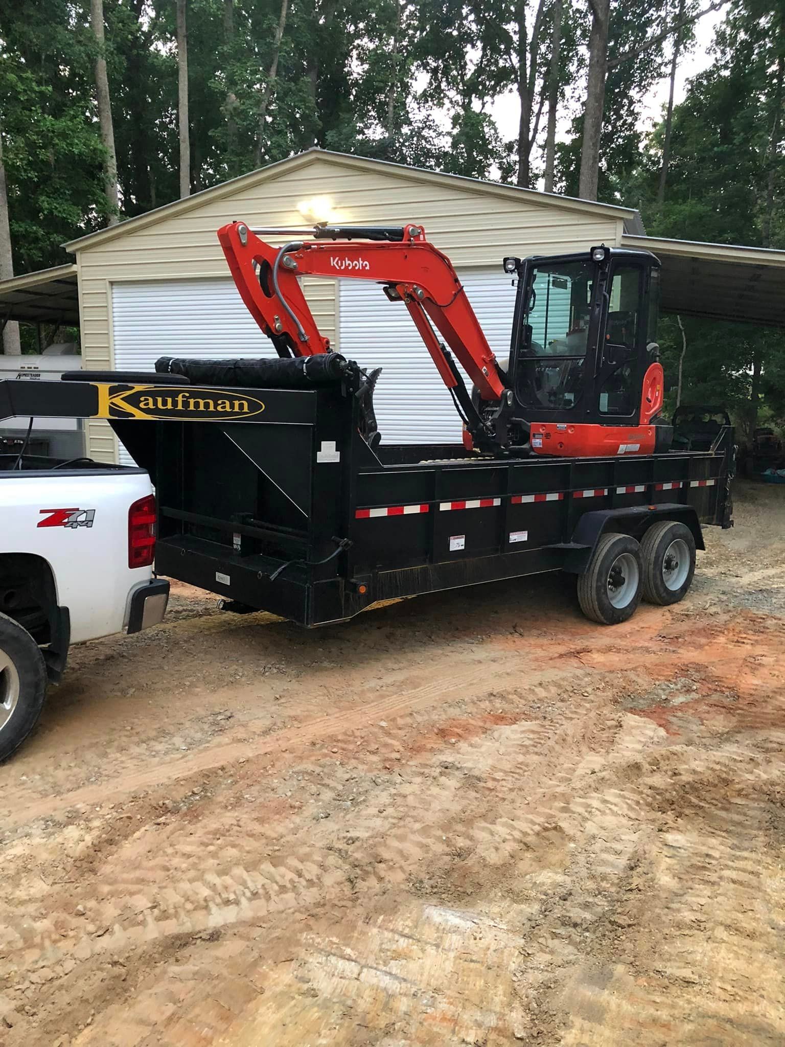 A dump truck with a crane attached to it is parked in front of a garage.