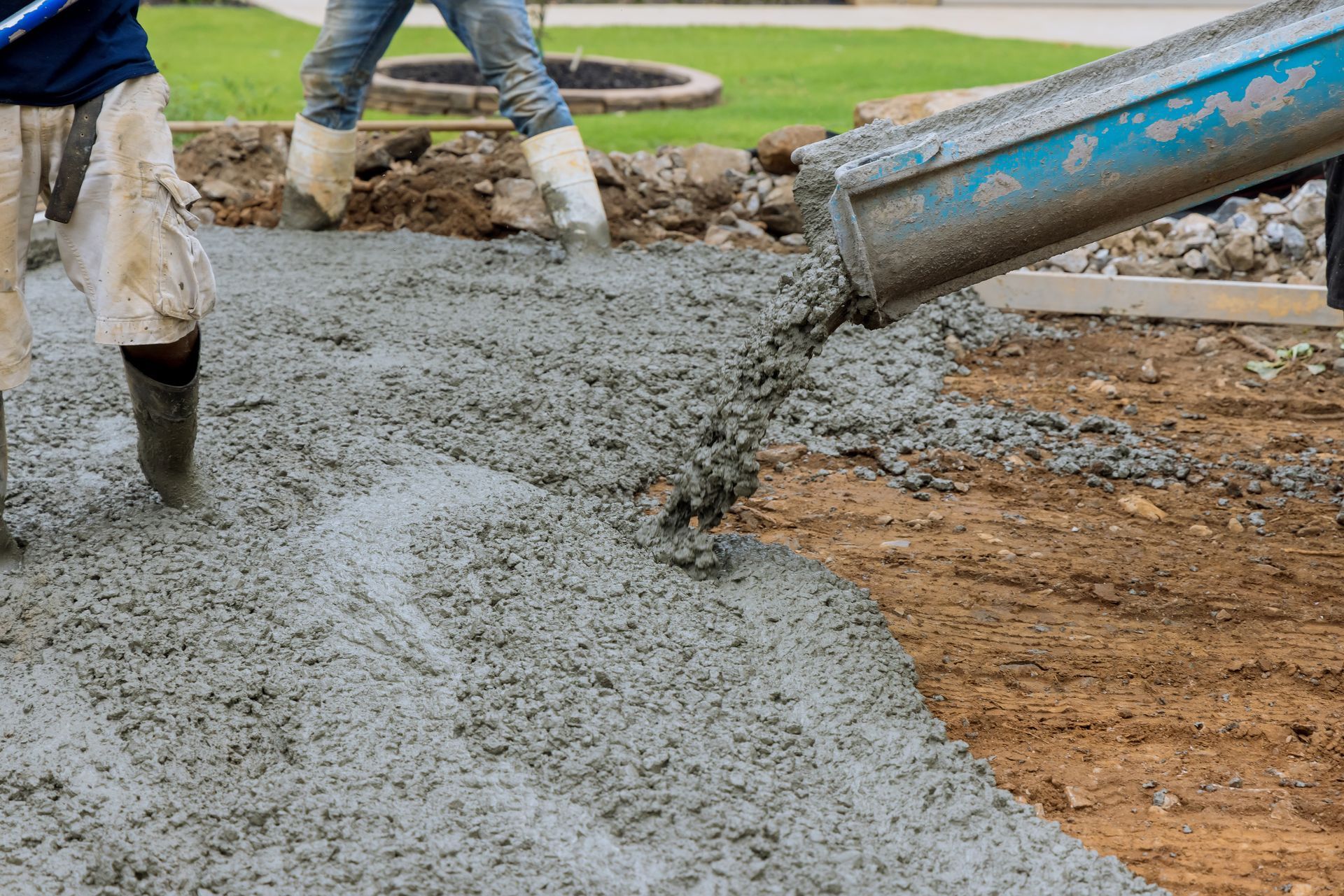 Workers pouring wet concrete for a sidewalk foundation outdoors