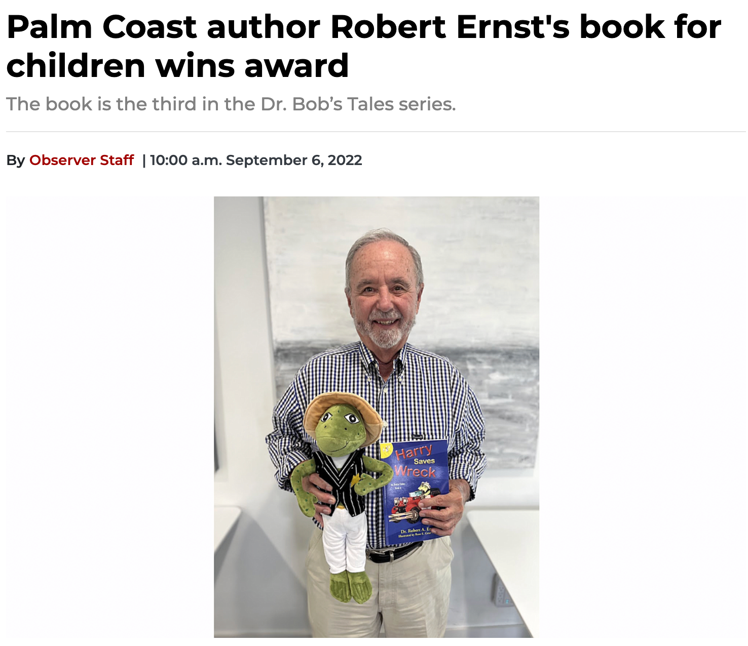 Author Robert Ernst holding a book and a frog toy, celebrating his award-winning children's book.