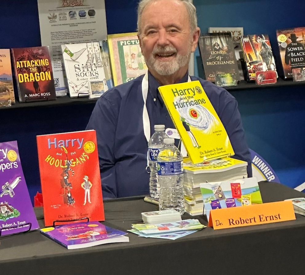 Author Robert Krusi at a book display, smiling, with several of his books visible.