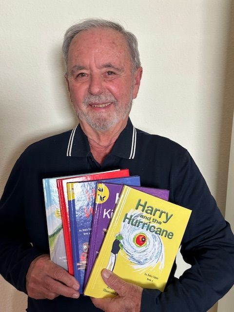 Man holding children's books, smiling. Includes titles