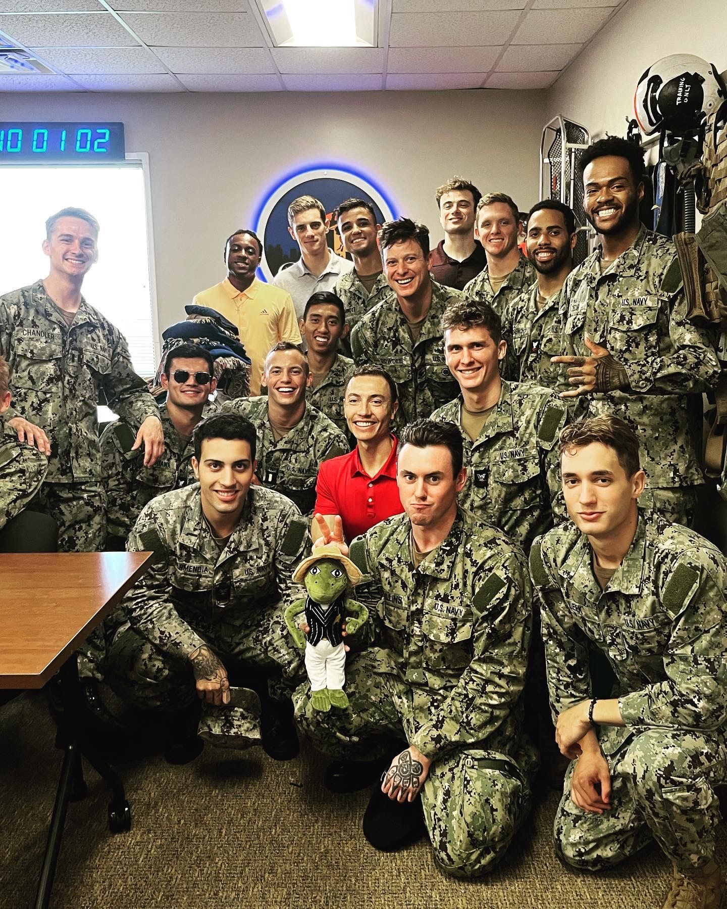Group of people in navy camouflage uniforms, smiling and posing indoors.