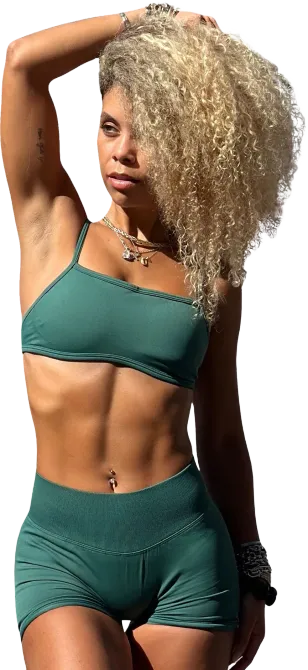 A woman in a pink sports bra and maroon leggings is wearing headphones.