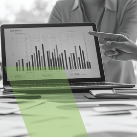 Person points at a laptop showing a bar chart in an office setting