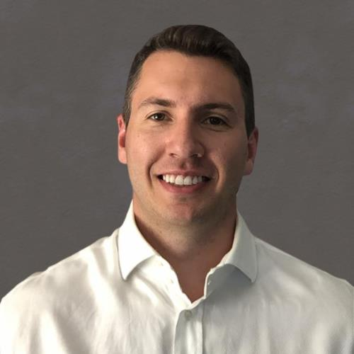Portrait of a smiling person in a white shirt against a gray background
