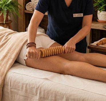 Mujer recibiendo un masaje de espalda en una camilla de spa con toallas blancas.
