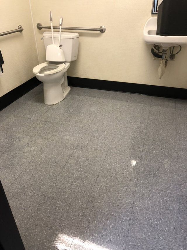 A bathroom with a toilet , sink and handrails.
