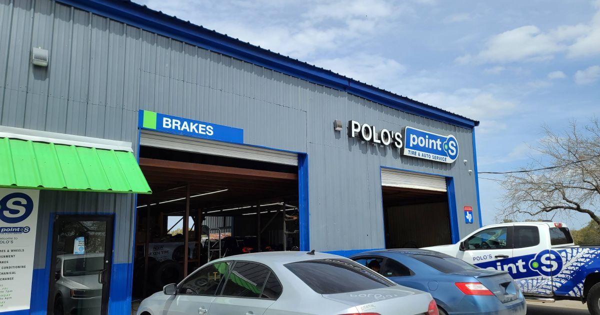 The exterior of Polo’s Point S automotive repair shop, featuring blue and gray siding with cars parked in front.
