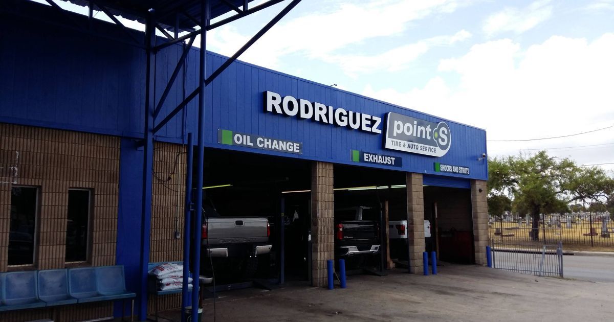 Blue exterior of Rodriguez Point S auto repair shop, featuring open service bays and signs for oil changes and tires.