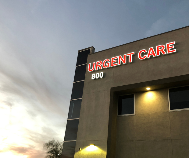 Urgent care clinic building at dusk with red illuminated sign and warm exterior lights