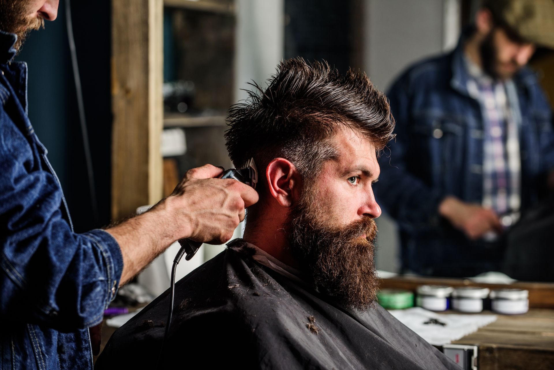 A man is getting his hair cut by a barber in a barber shop.