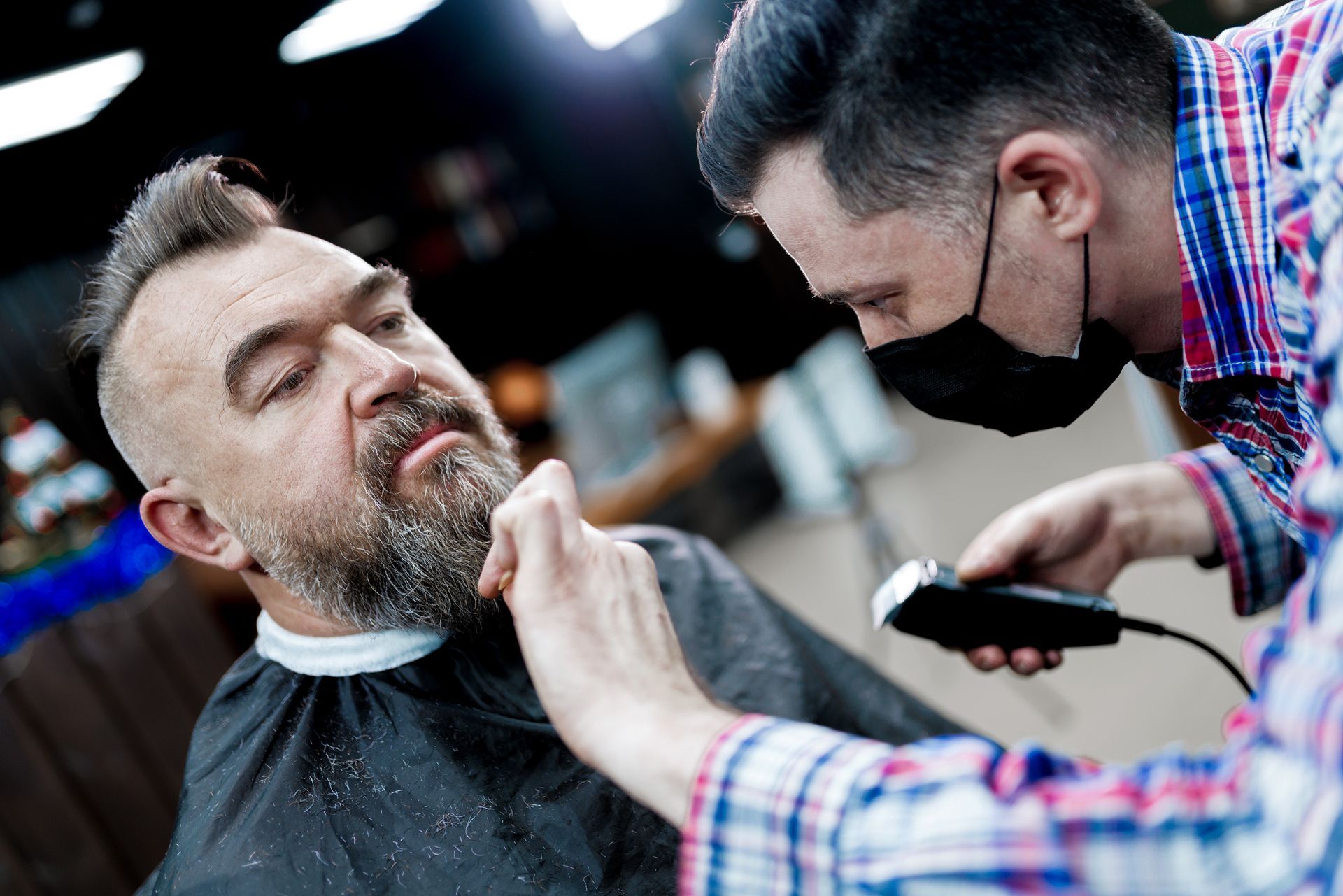 A man is getting his beard cut by a barber in a barber shop.