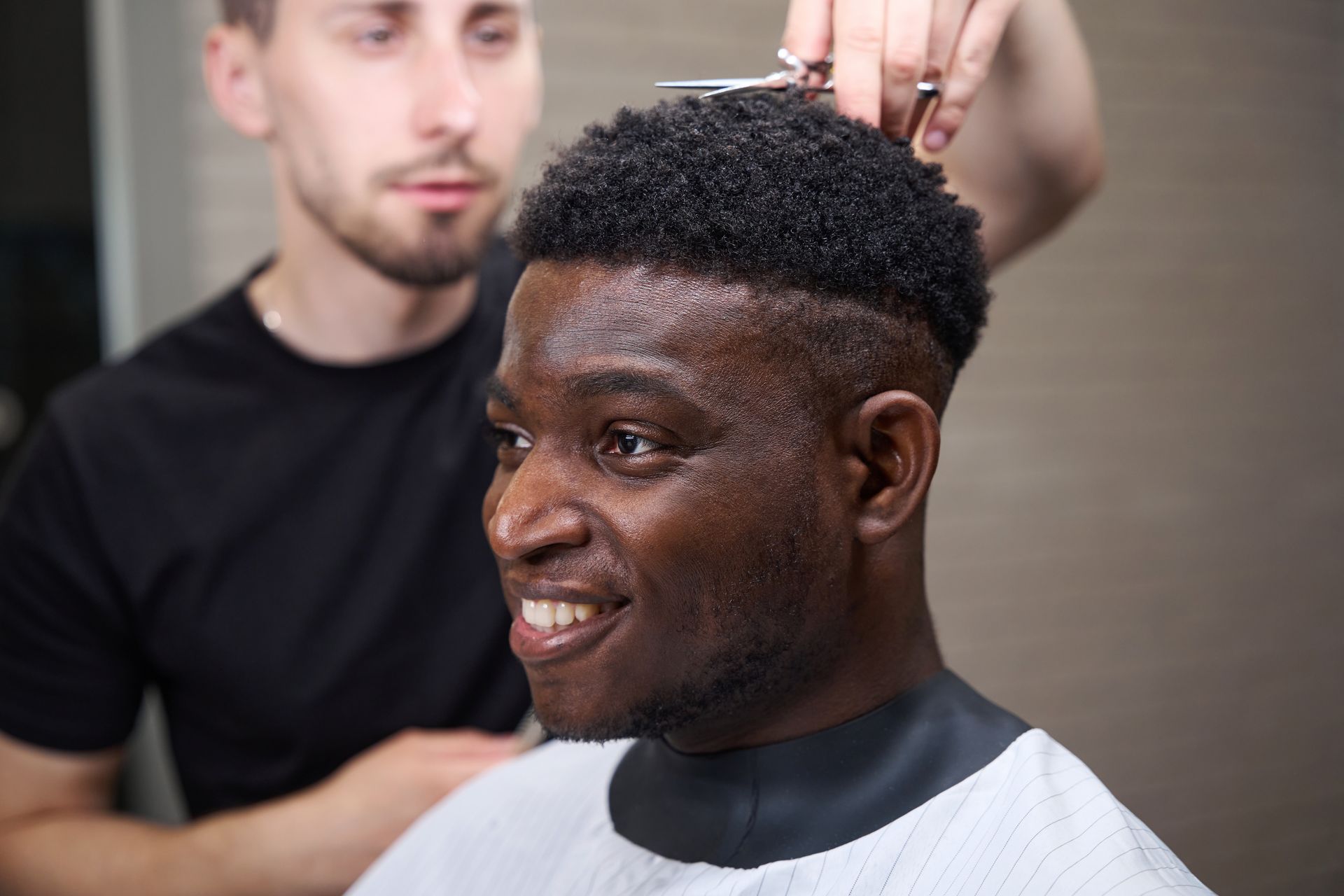 A man is getting his hair cut by a barber in a barber shop.