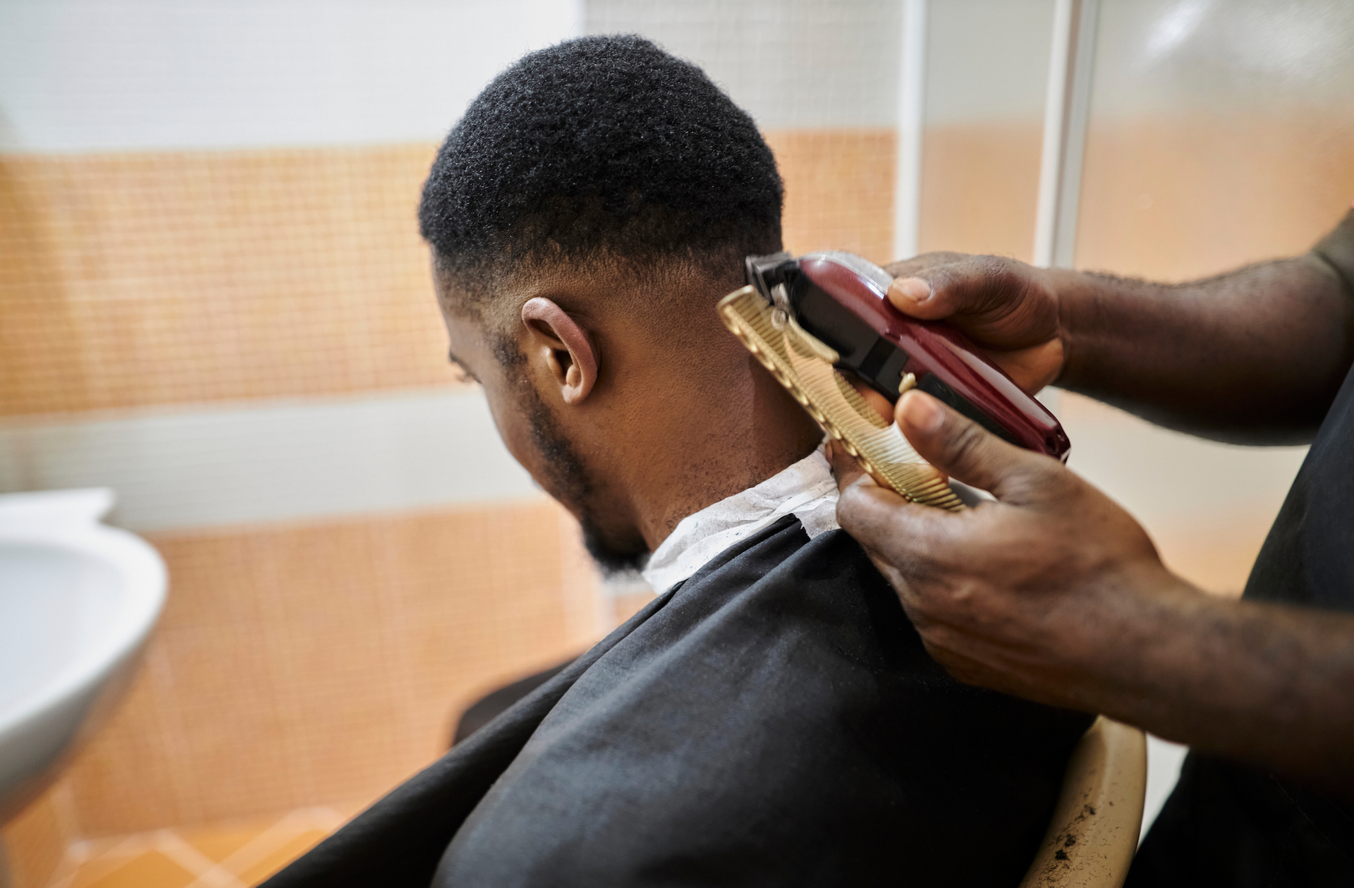 A man is getting his hair cut at a barber shop.
