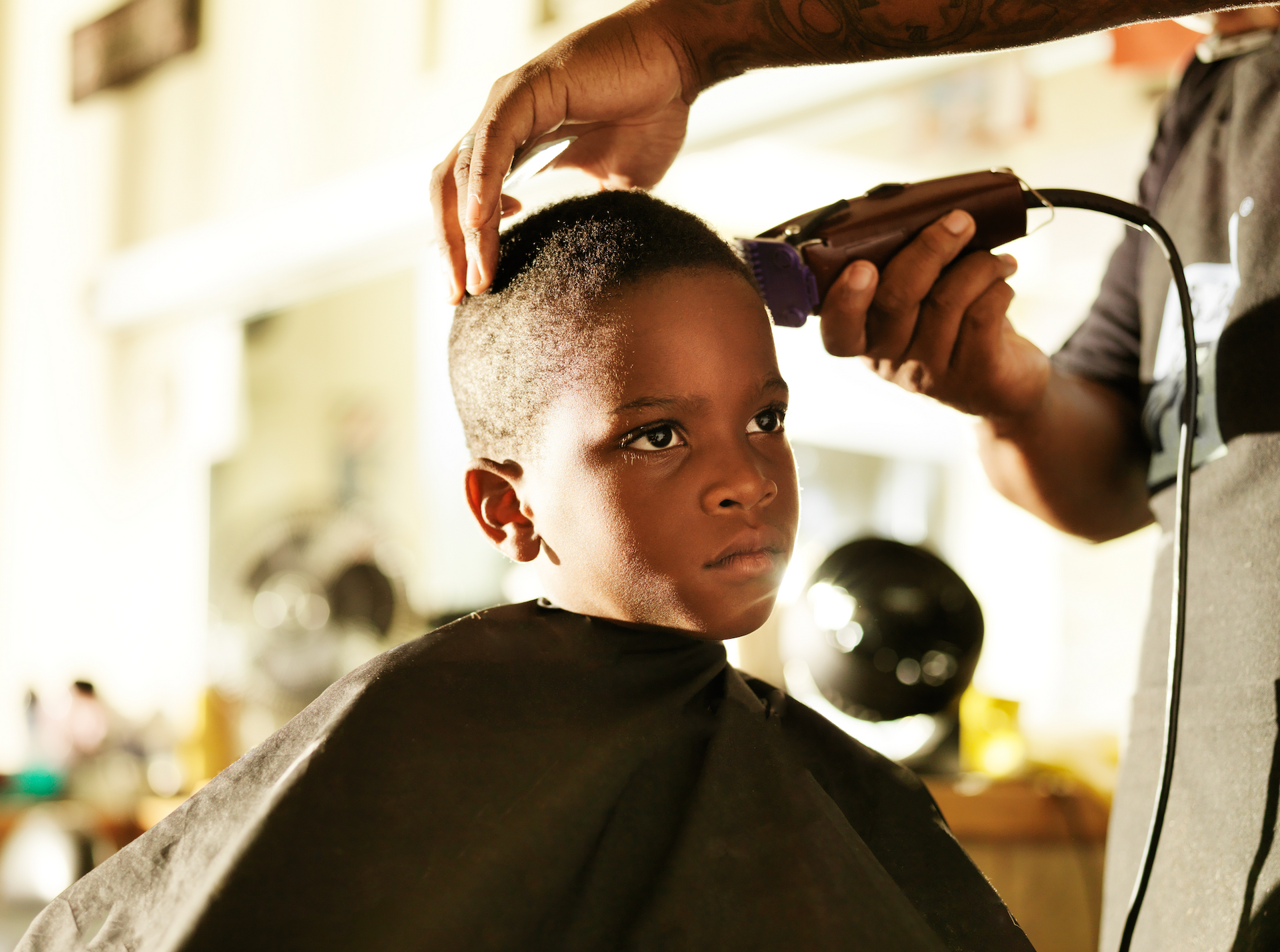 A young boy is getting his hair cut by a barber