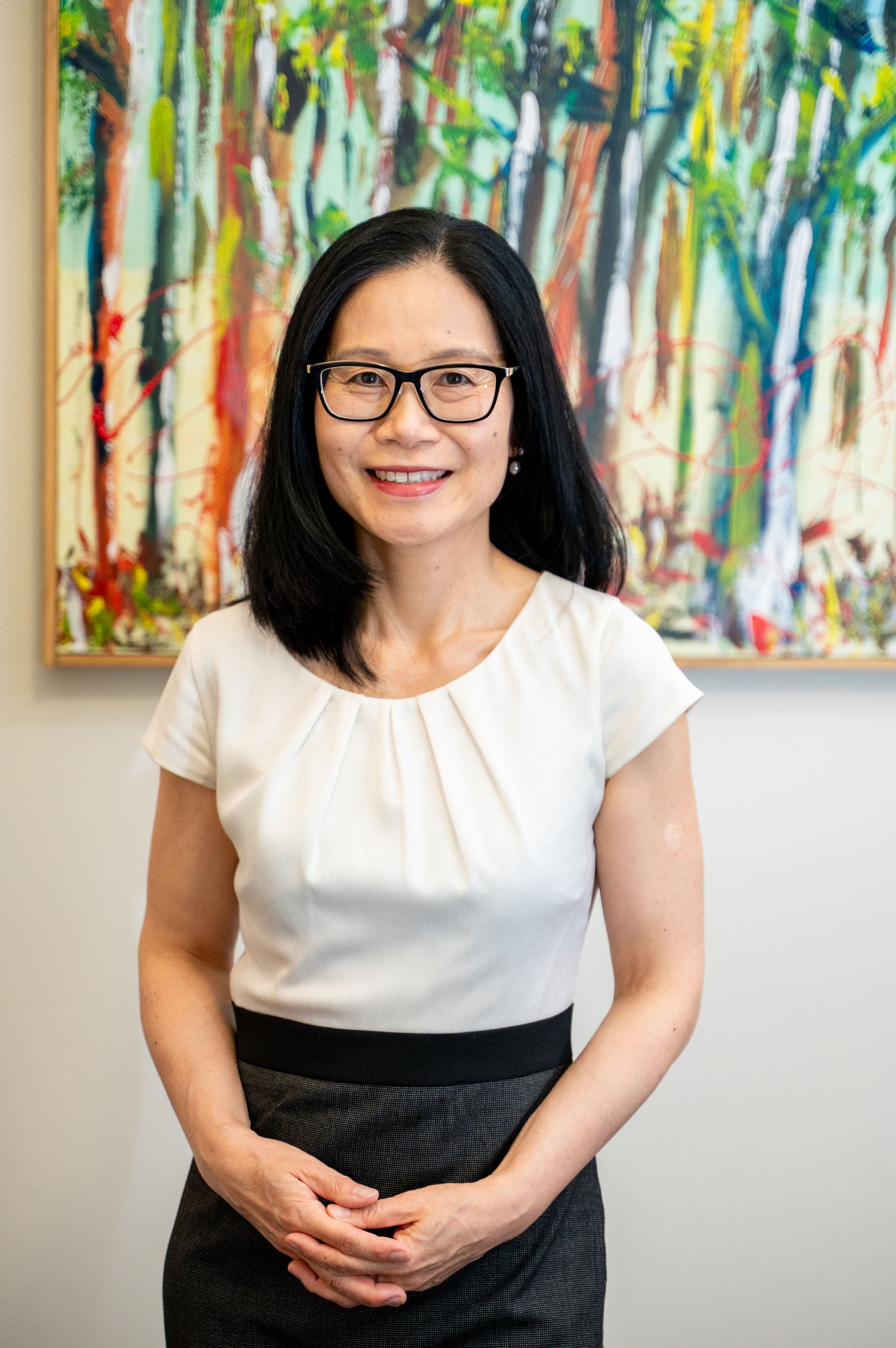 Woman wearing glasses smiles at the camera, light floral top.