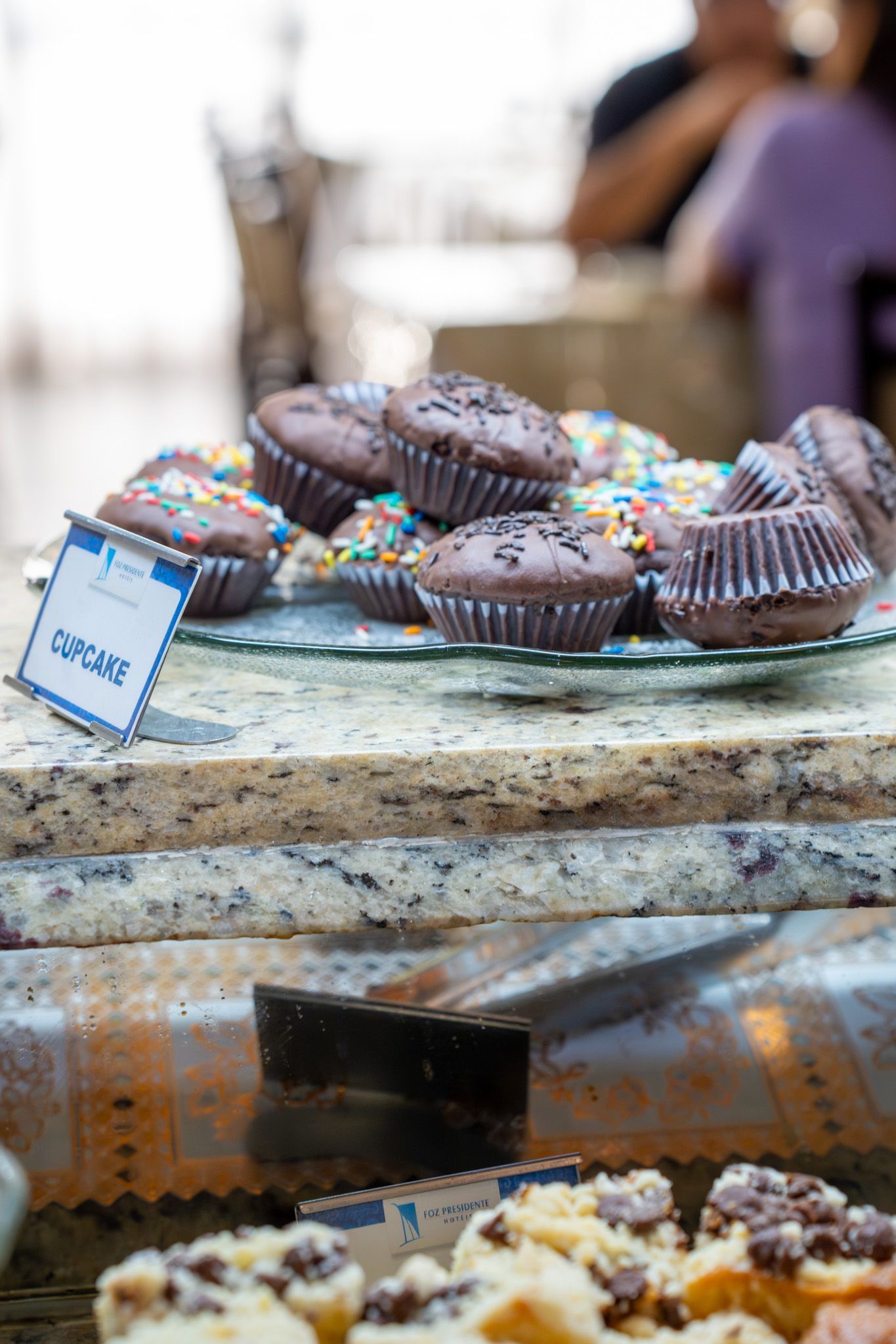 Muffins de chocolate em uma bandeja em uma mesa de buffet com uma pequena etiqueta e fundo desfocado.