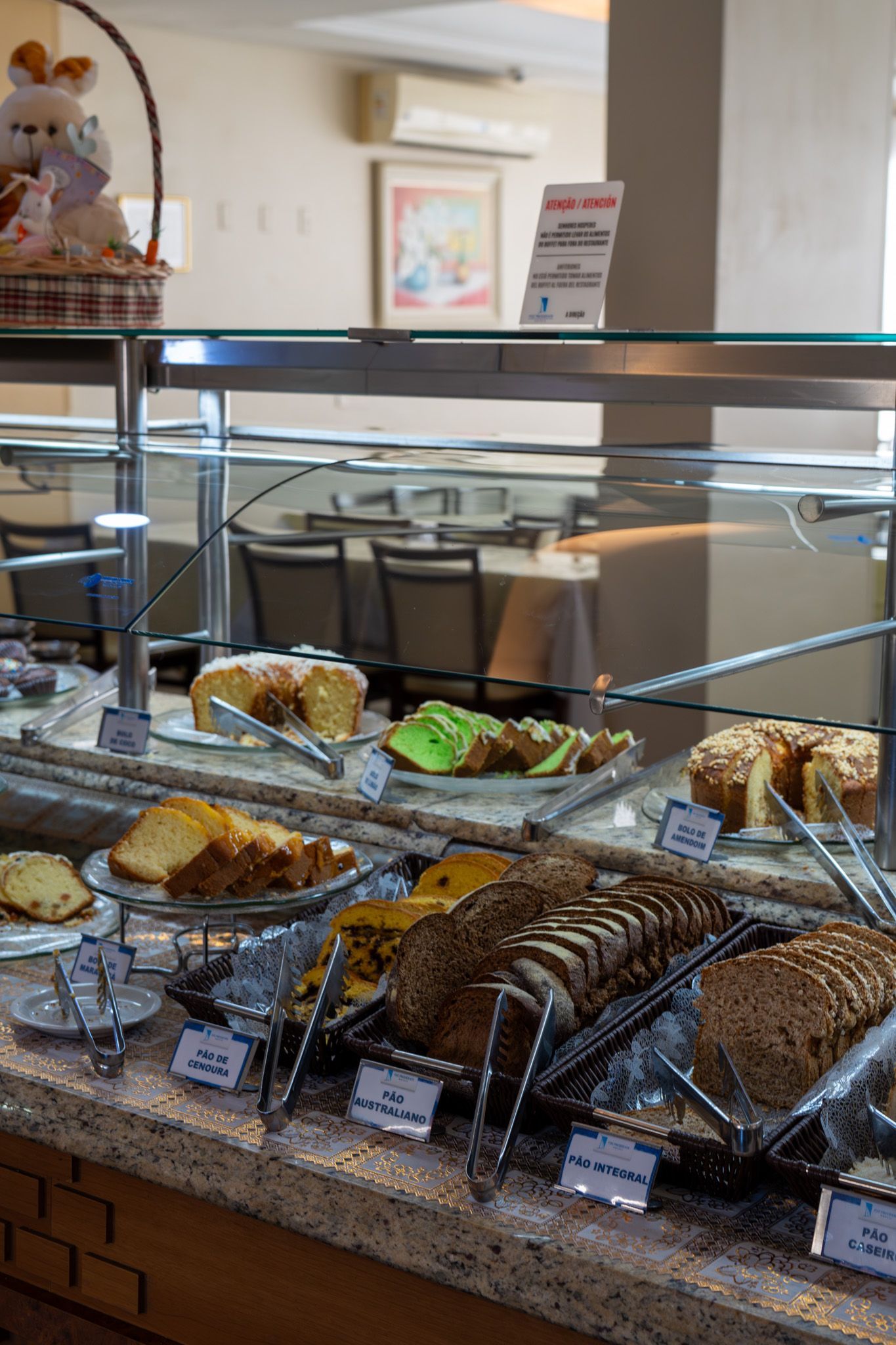 Vitrine de padaria com uma variedade de doces e sanduíches sob vidro.
