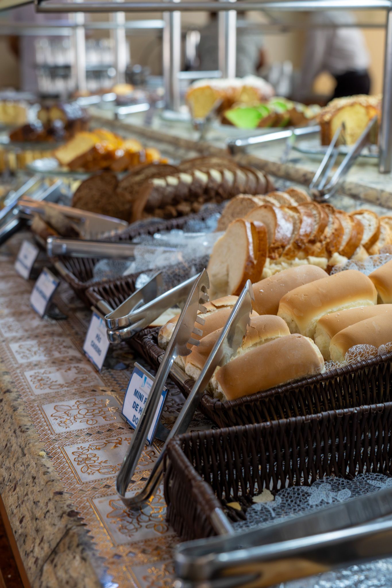 Buffet de padaria com uma variedade de doces e pães em cestas e bandejas de vime.