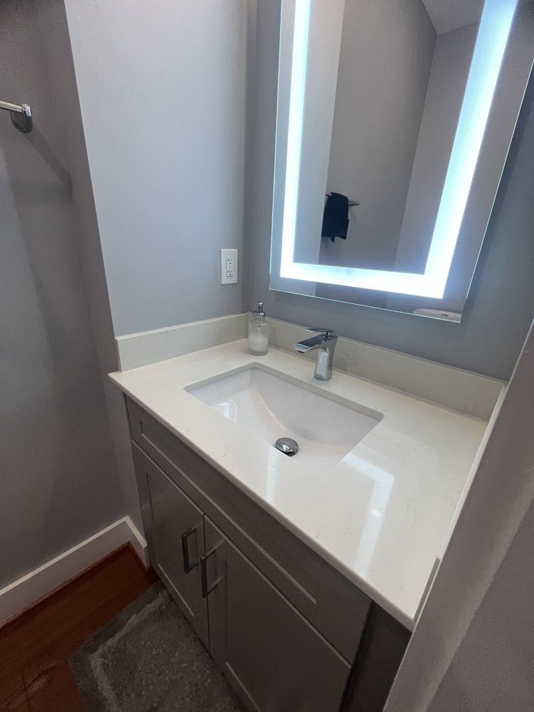 A bathroom with a sink , mirror and cabinets.