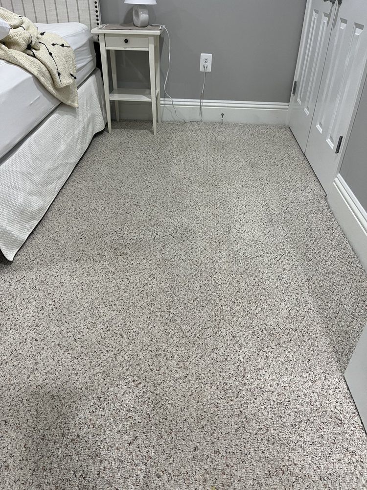 A bedroom with a bed , nightstand , and carpeted floor.