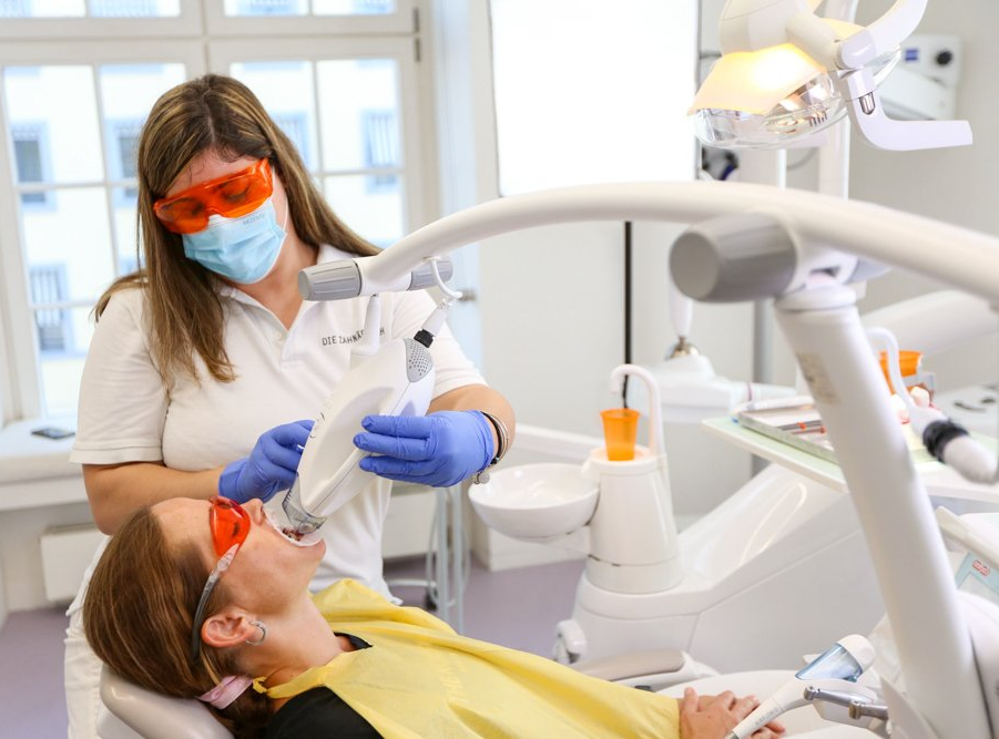 A woman is getting her teeth whitened by a dentist in a dental office.
