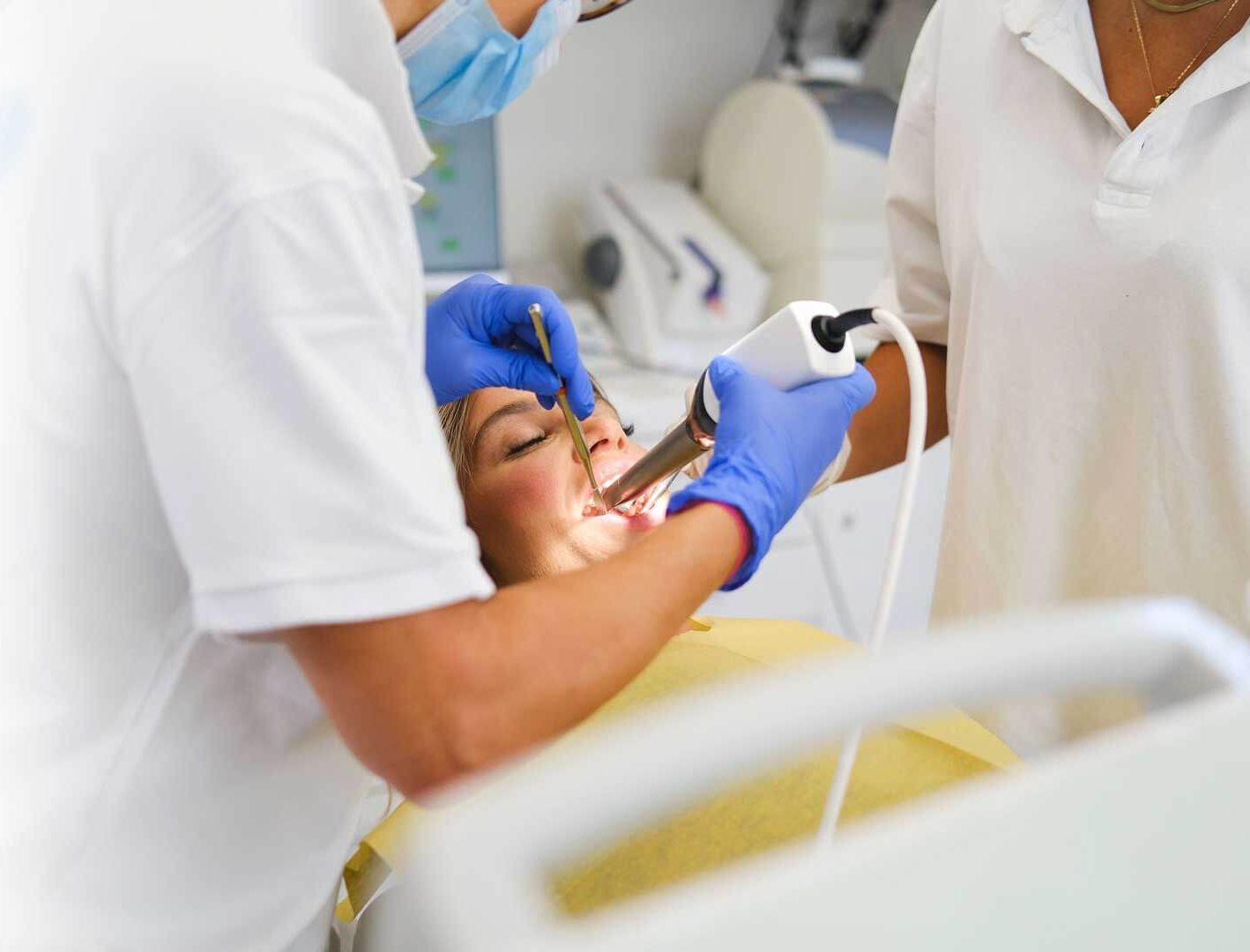 A dentist is examining a patient 's teeth in a dental office.