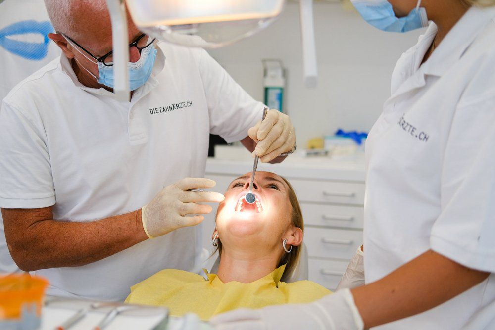 A woman is getting her teeth examined by a dentist in a dental office.