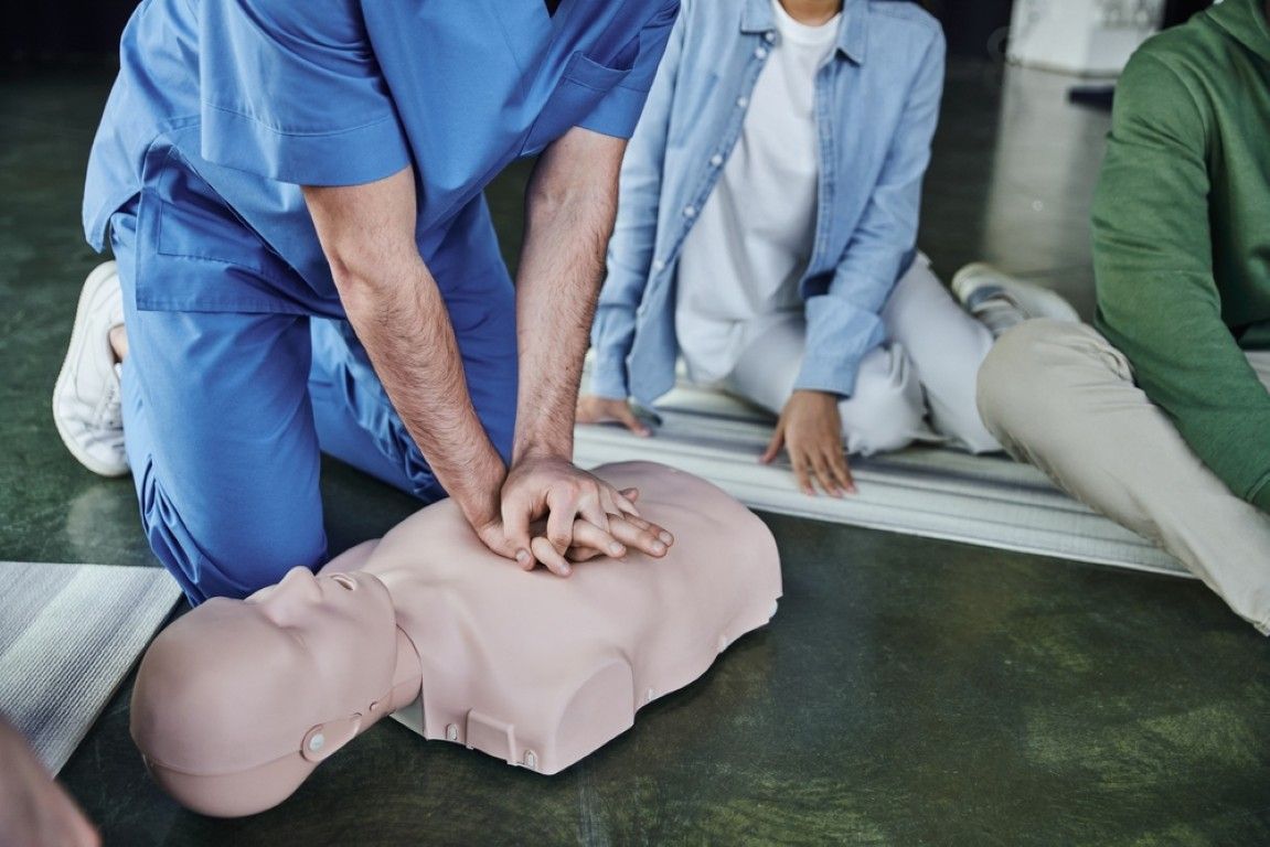 Manikin being given chest compressions during a CPR training session. Other trainees watch.