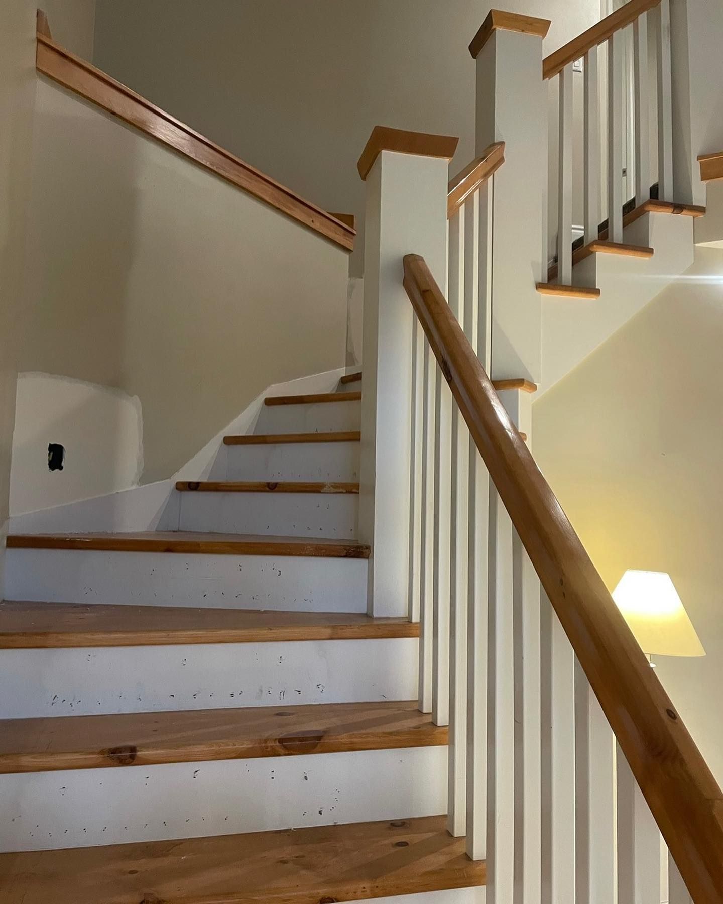 Staircase with white risers, wooden treads, and light wooden handrails and balusters. Light walls.
