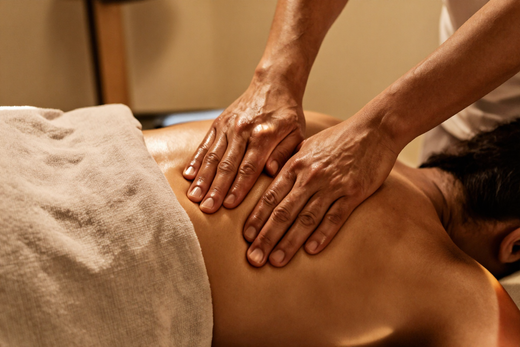 Hands performing deep tissue massage on a shoulder