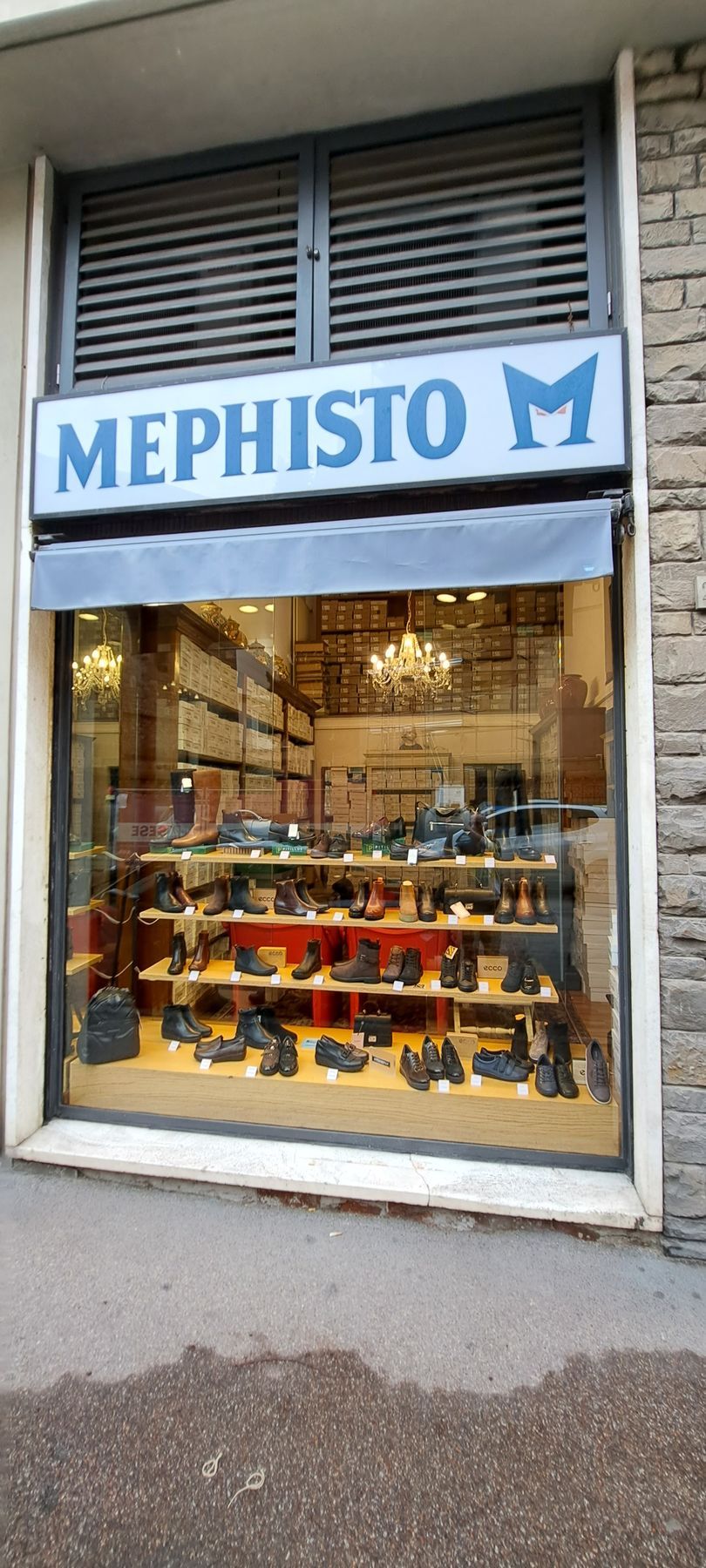 Vetrina del negozio di scarpe Mephisto con esposizione di scarpe e cartello blu.