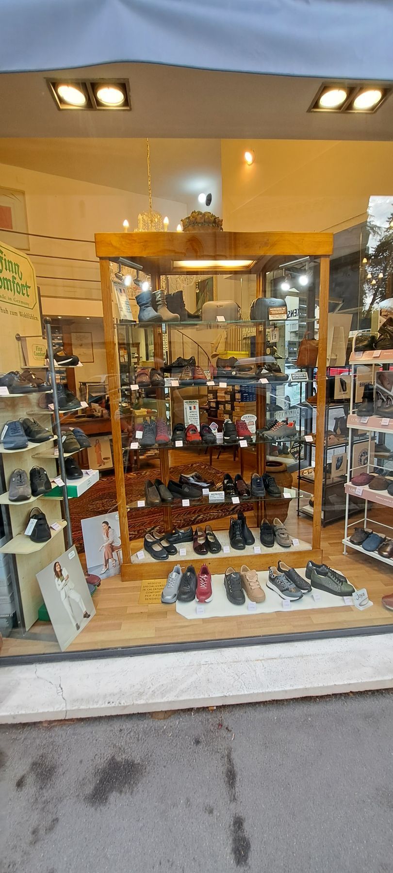 Vetrina di un negozio di scarpe con diverse scarpe sugli scaffali. Struttura in legno con illuminazione interna intensa.