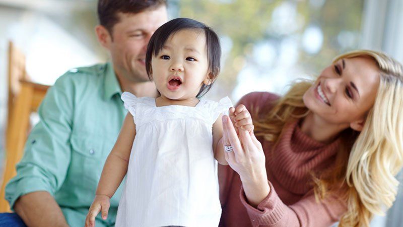 two adults smile at young child