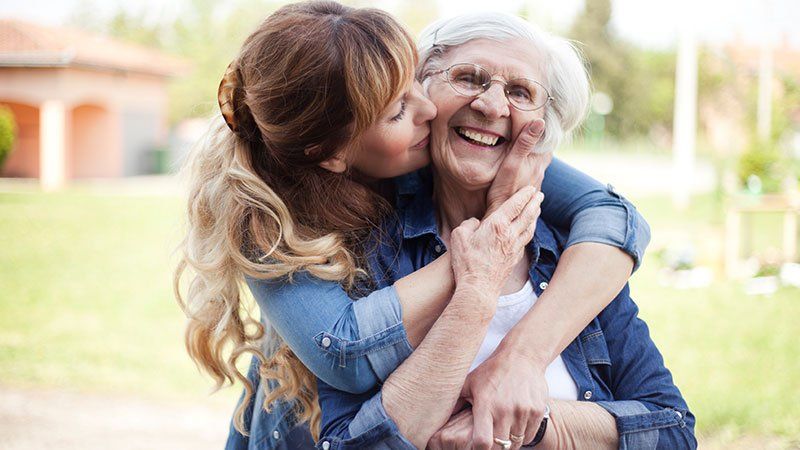 younger woman kisses older woman on the cheek