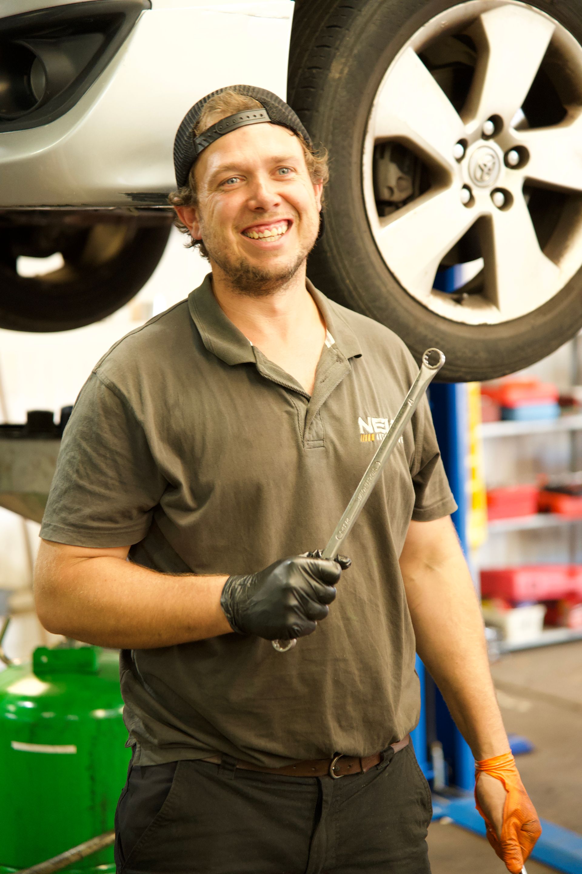A Man Holding A  Spanner In Front Of A Tyre Of A Car On A Wrench — NEID Automotive In North Gosford, NSW