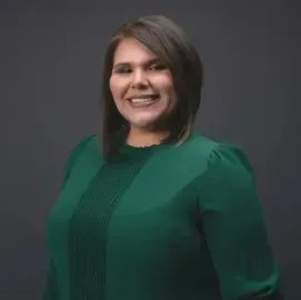 Studio portrait of a smiling person in a green top against a gray background
