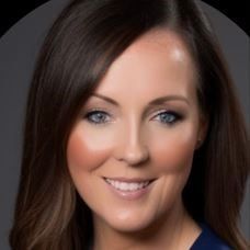 Studio headshot of a smiling woman with dark hair against a gray background