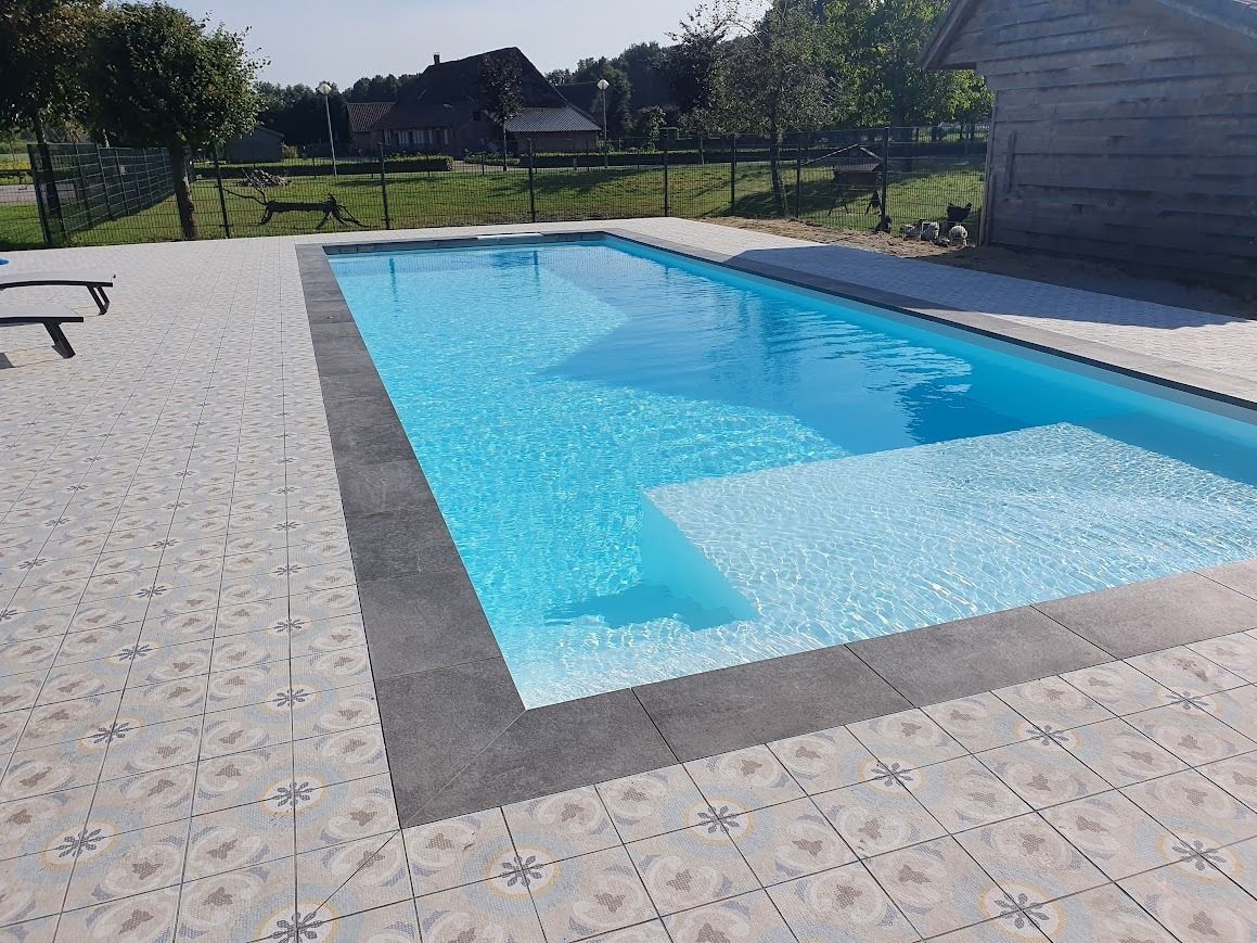 Rechthoekig zwembad (PanelPool) met lichtblauw water en trappen, omgeven door sierstenen.