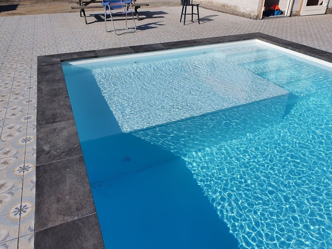 Een zwembad (PanelPool) met helderblauw water en trappen, omgeven door grijze stenen.