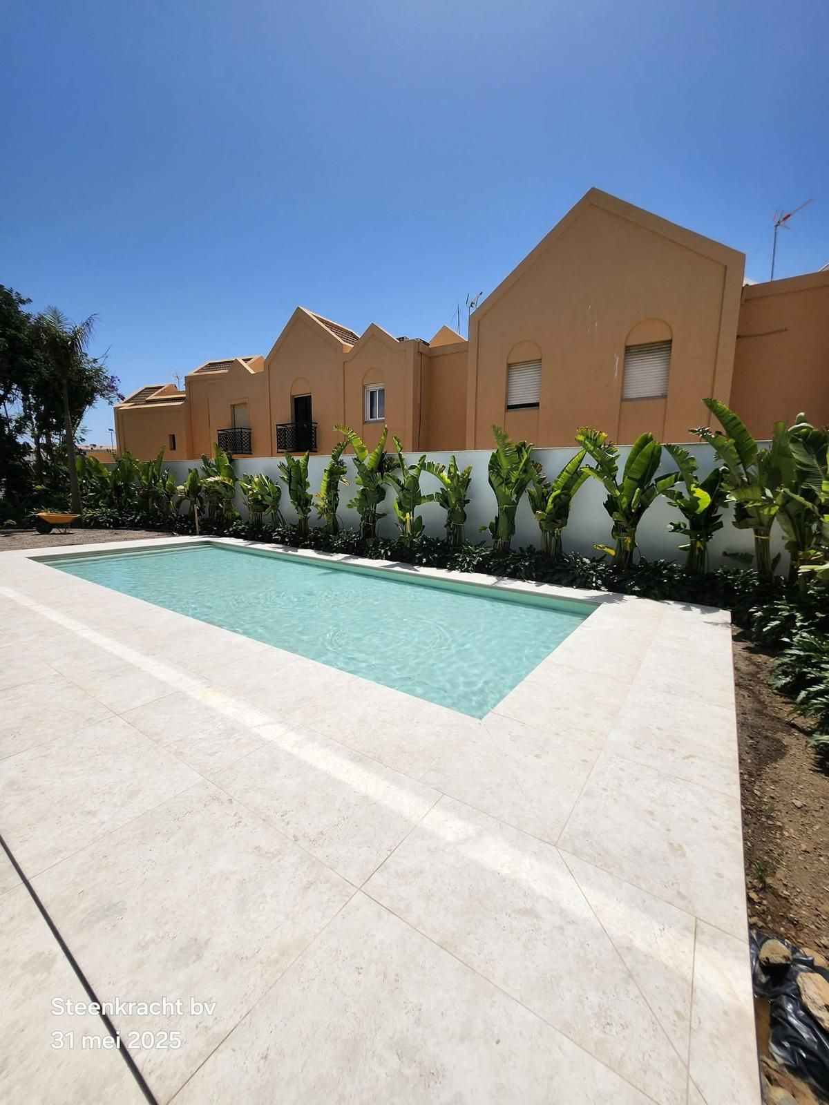 Een rechthoekig MagicPool voor beige gebouwen met een helderblauwe lucht.
