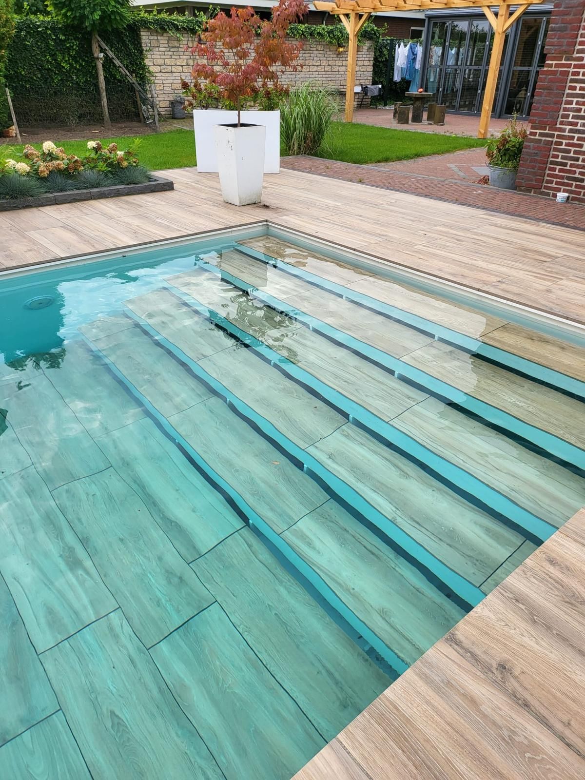 MagicPool met houtlook trap, ondergedompeld in helder water, omgeven door een houten terras.